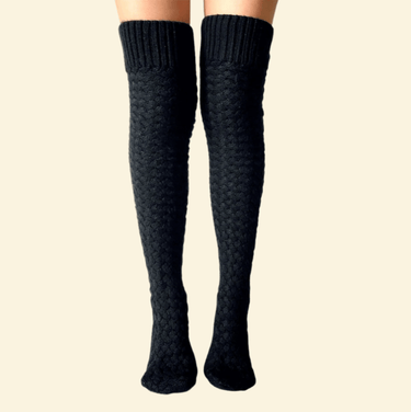 Long black thermal knee-high socks worn on legs against a cream background